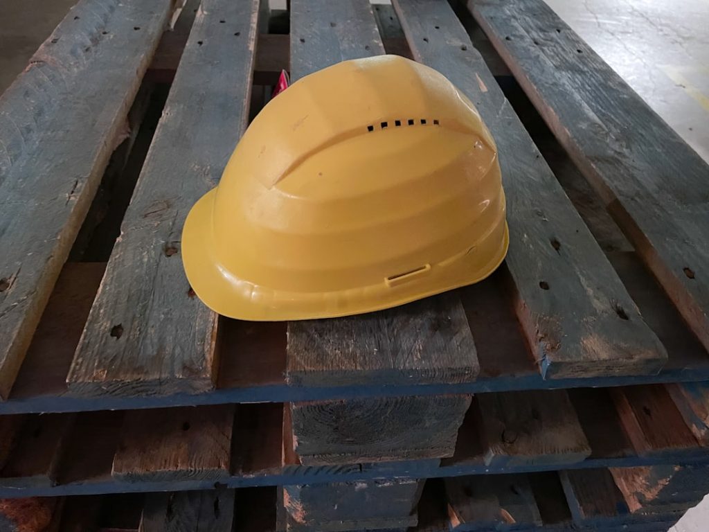 a-yellow-hard-hat-rests-on-a-wooden-pallet-cigfvtfu39i