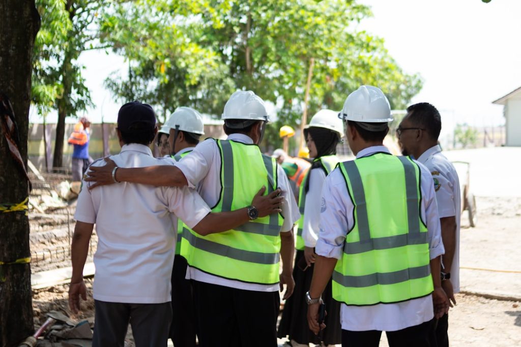 construction-workers-in-hard-hats-and-vests-huddle-together-nlxv-jcfshc