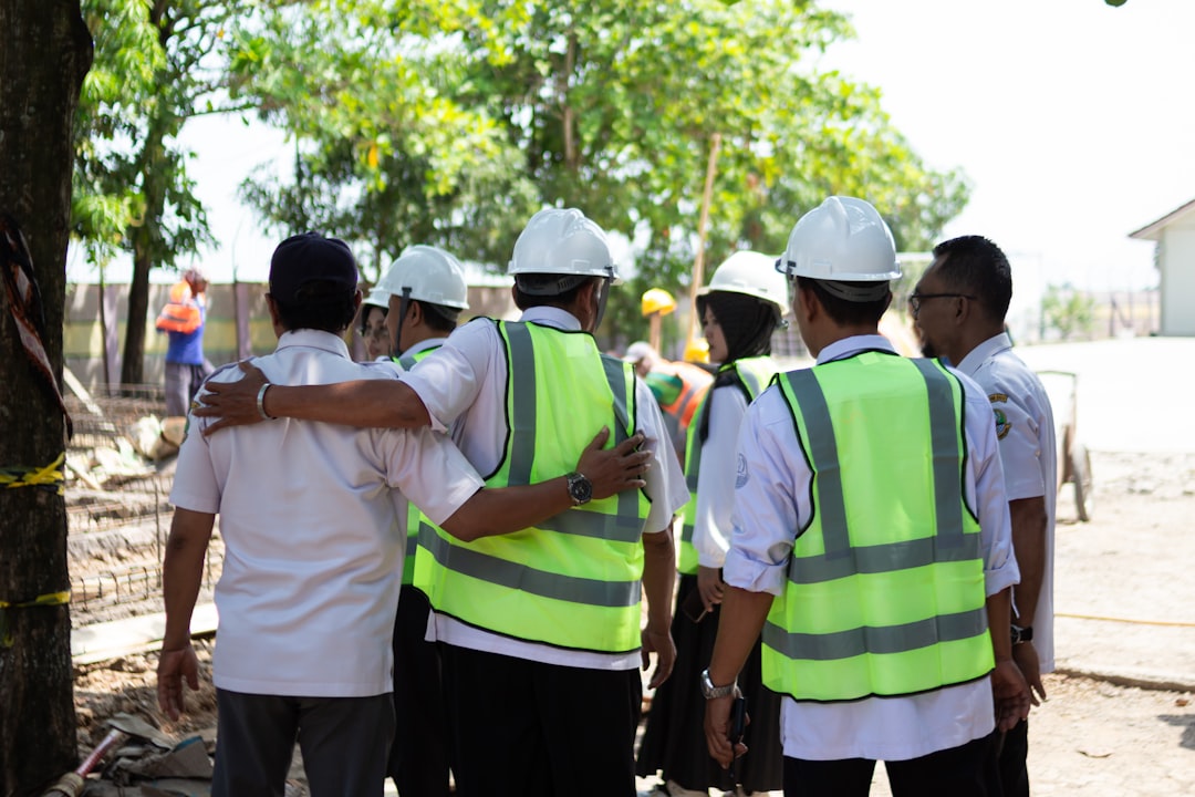 construction-workers-in-hard-hats-and-vests-huddle-together-nlxv-jcfshc