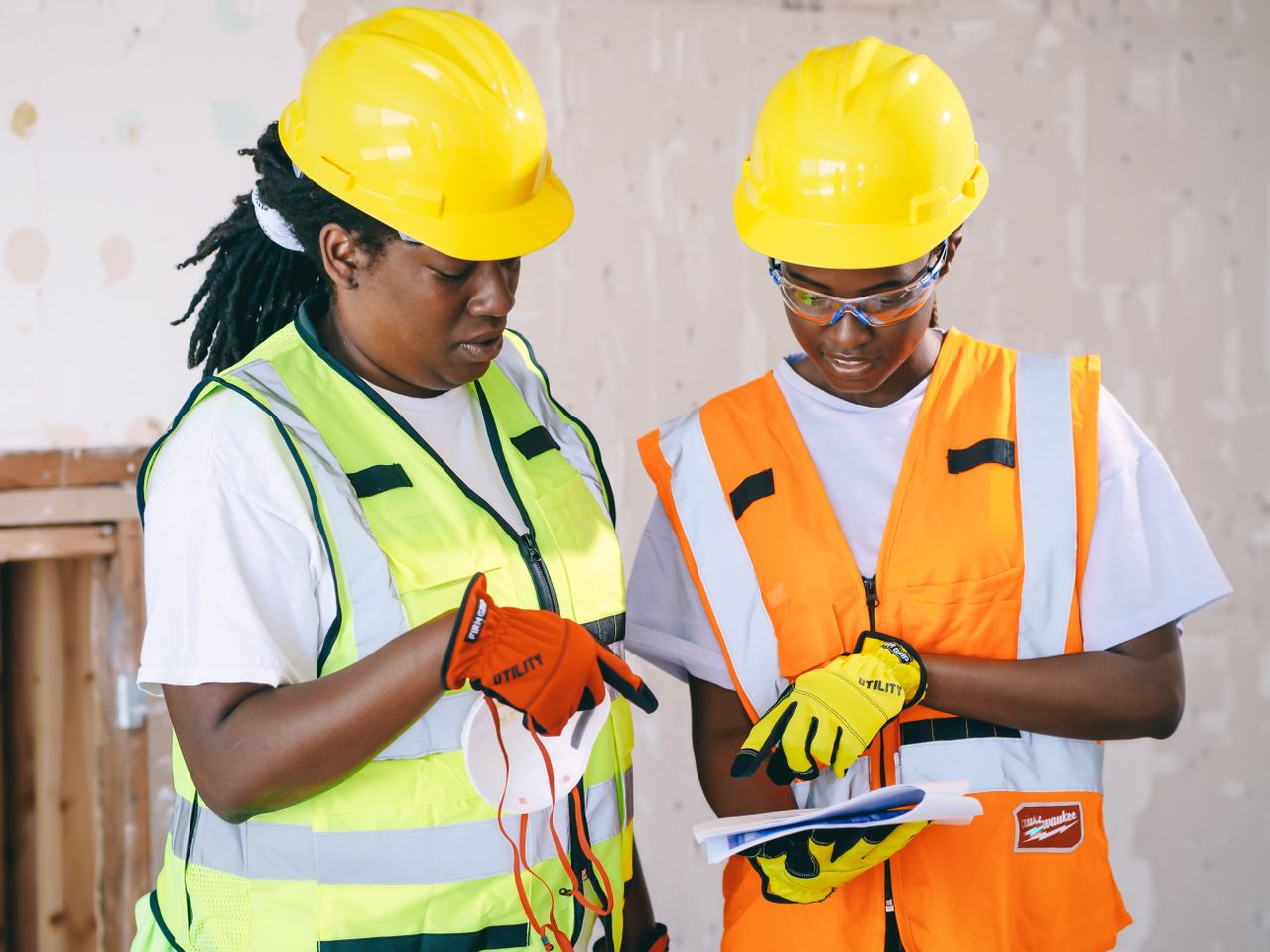 Two engineers in safety gear review construction plans, showcasing teamwork and safety.