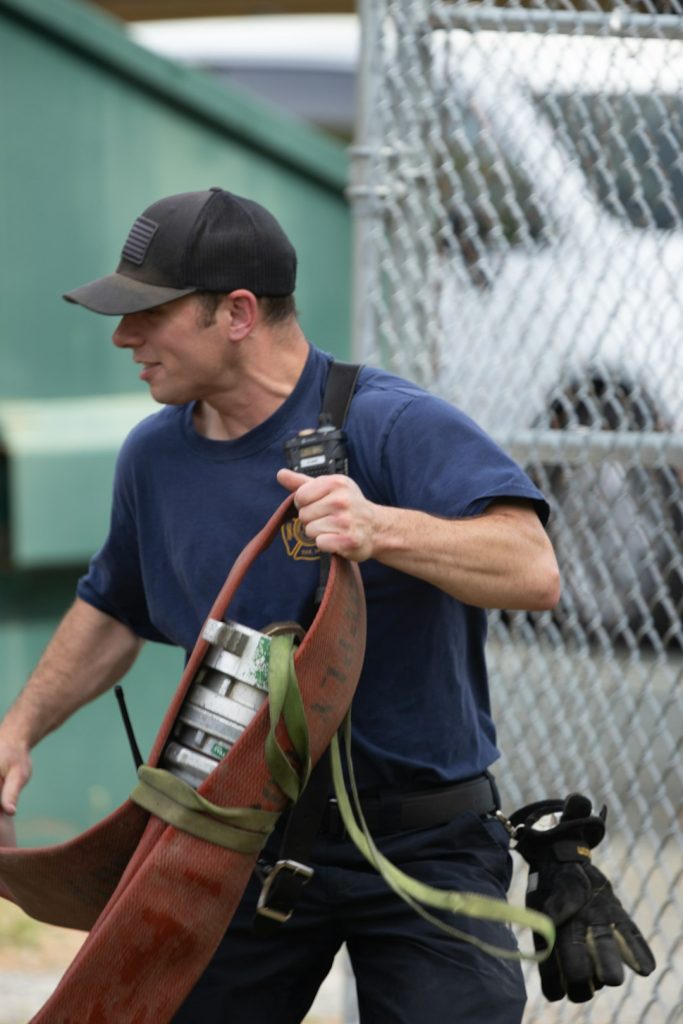 firefighter-carrying-a-hose-with-a-glove-attached-jsejq-m3m2o